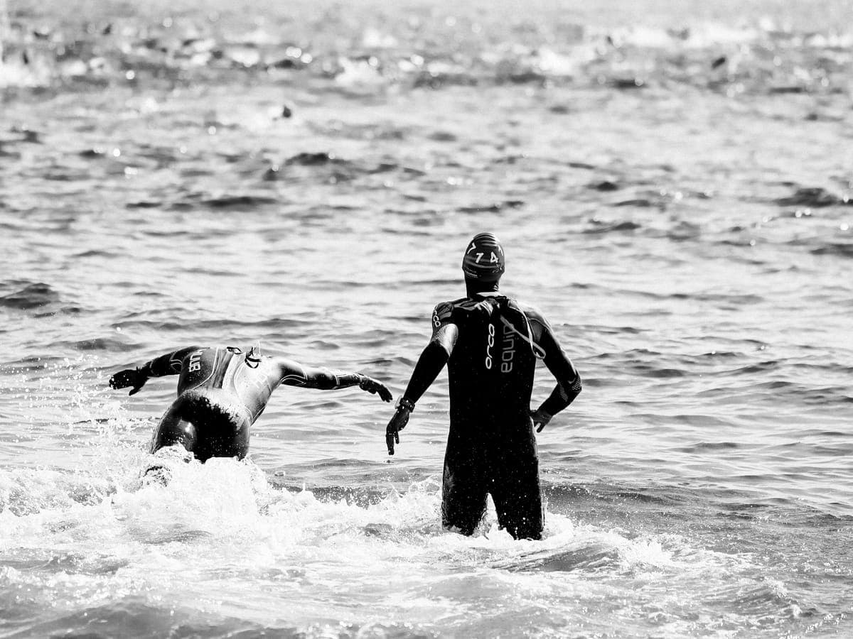 Two triathletes swimming in open water during a race.