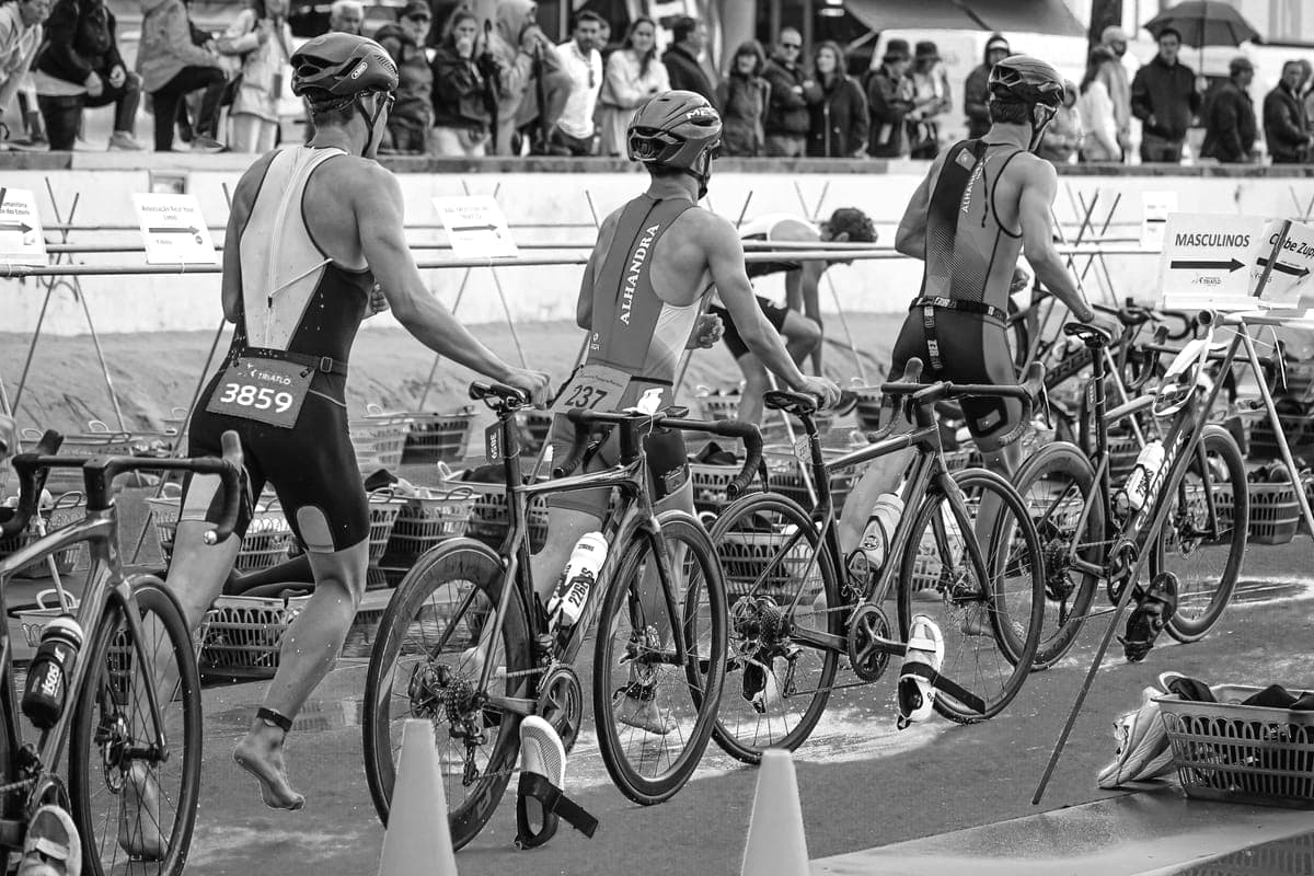 Triathletes moving through the transition area from swimming to cycling.